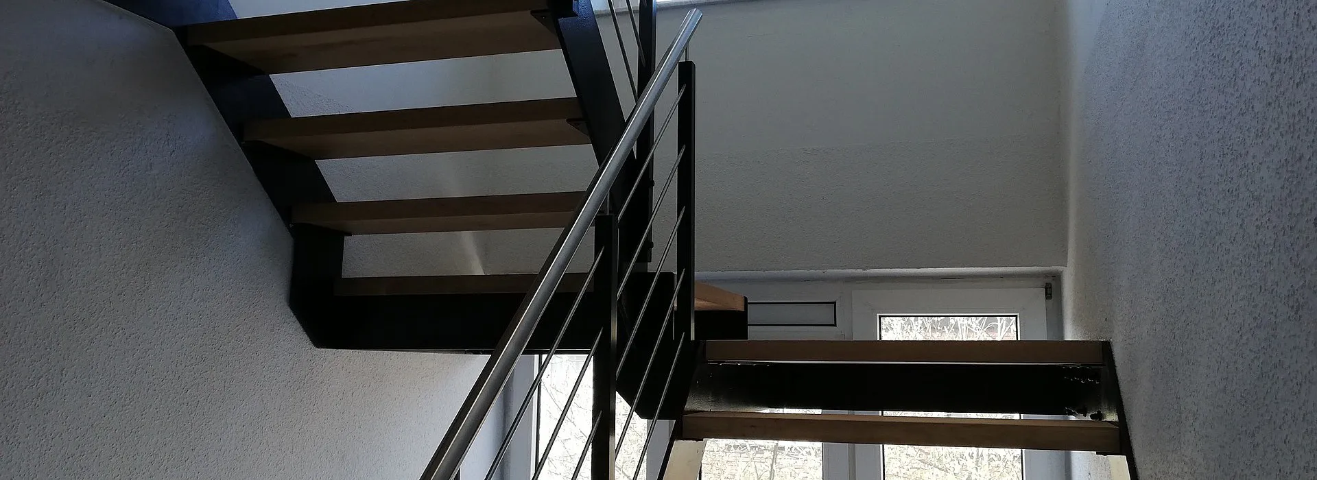 Indoortreppe mit Holzstufen und Stahlgeländer aus schwarzen und silbernen Elementen