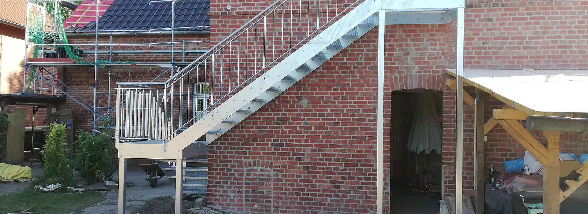Outdoor Stahltreppe in silber mit Stahlgeländer an Hauswand, seitenansicht