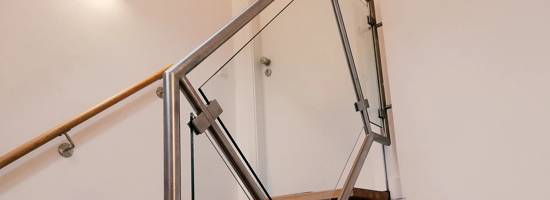 Geländer im Treppenhaus aus Glaselementen und Edelstahl, Handlauf aus Edelstahl