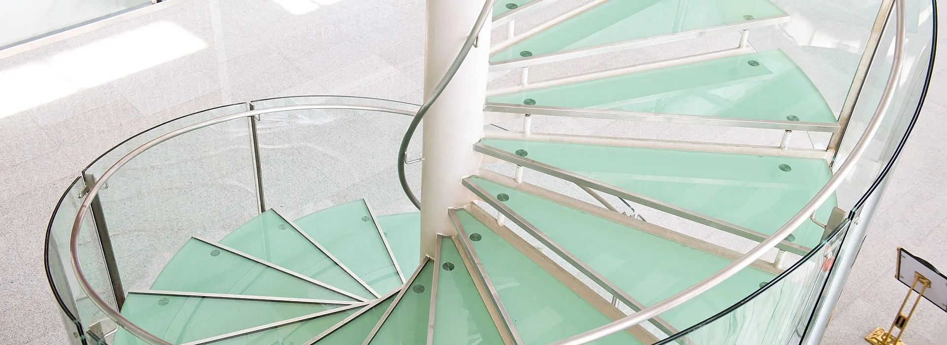 Spindeltreppe mit Stufen aus Glas, Glasgeländer und Metallhandlauf