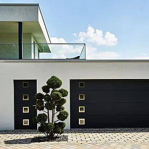 Anthrazit farbenes Garagentor und Haustür mit jeweilsvier kleinen quadratischen Fenstern und silbernem Rahmen